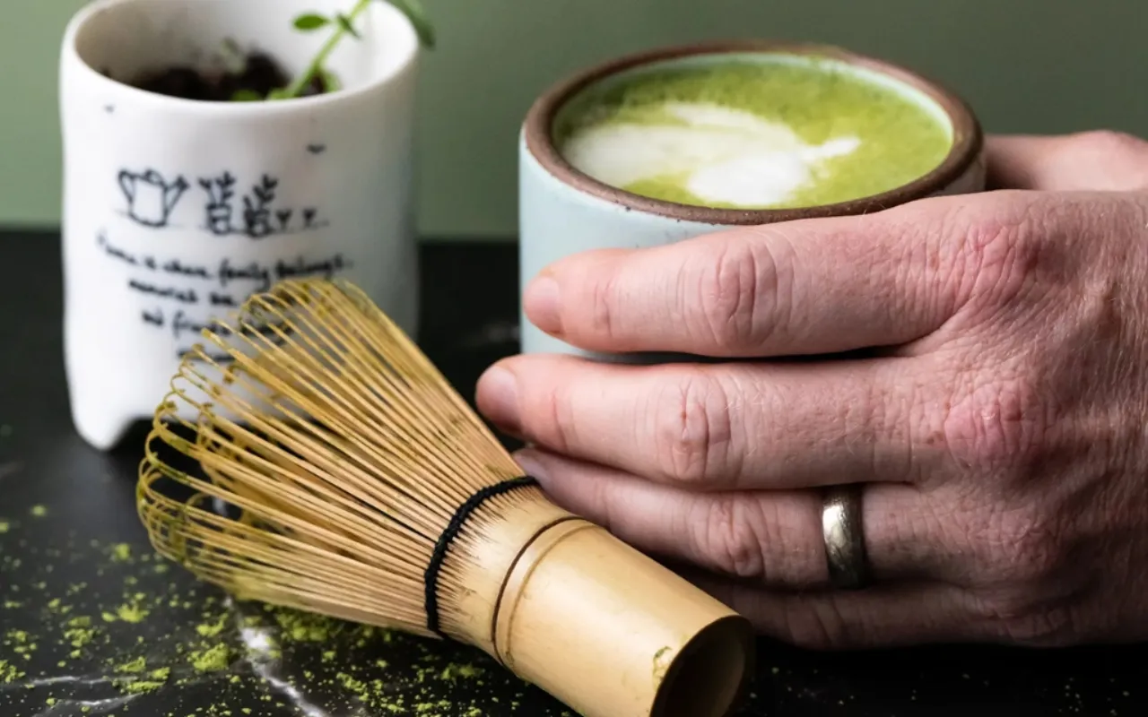 Hand holding a warm cup of matcha